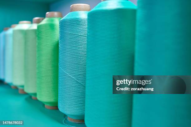 side view of turquoise colored series yarn spindles - nylon stockfoto's en -beelden