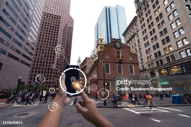human hand using mobile phone in downtown city street against illuminated urban skyscrapers in boston usa. - washington dc icon stock pictures, royalty-free photos & images