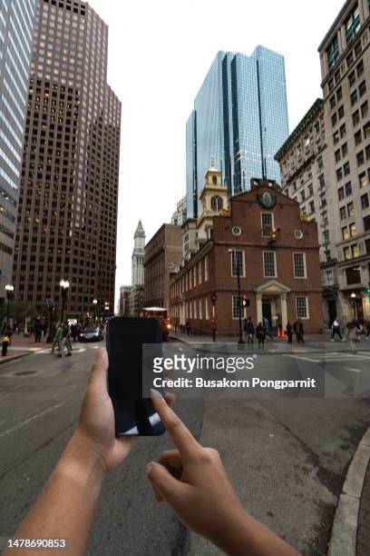 human hand using mobile phone in downtown city street against illuminated urban skyscrapers in boston u.s.a - u know stock pictures, royalty-free photos & images