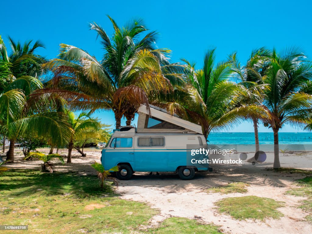 Van on a beach near palm trees, Mahahual village, coast of Quintana Roo state in Mexico