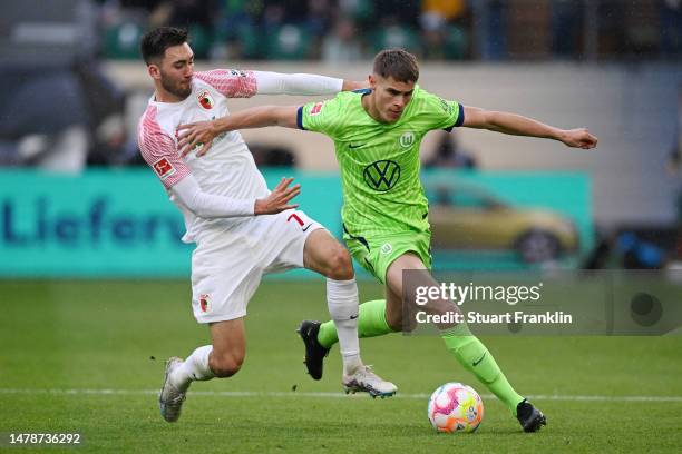 Micky van de Ven of VfL Wolfsburg is challenged by Dion Beljo of FC Augsburg during the Bundesliga match between VfL Wolfsburg and FC Augsburg at...