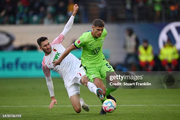 Micky van de Ven of VfL Wolfsburg is challenged by Dion Beljo of FC Augsburg during the Bundesliga match between VfL Wolfsburg and FC Augsburg at...
