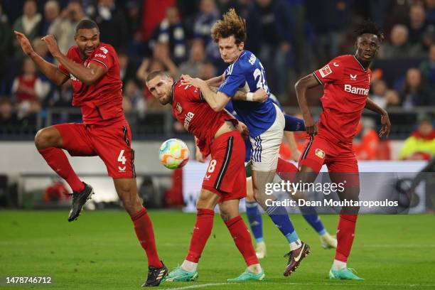Alex Kral of FC Schalke 04 battles for the ball with Jonathan Tah, Robert Andrich and Odilon Kossounou of Bayer 04 Leverkusen during the Bundesliga...