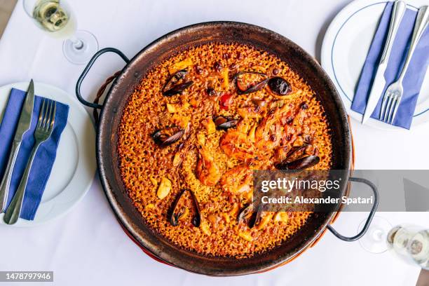 paella with seafood served for dinner at the restaurant, directly above view - paella stockfoto's en -beelden