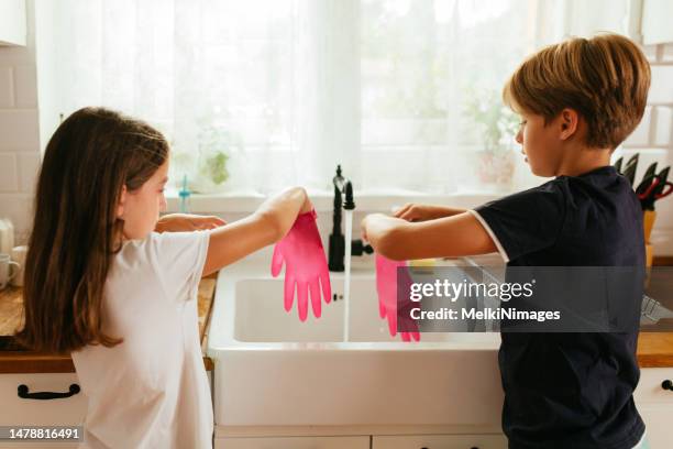 kinder haben spaß mit gummihandschuhen in der küche - kids with cleaning rubber gloves stock-fotos und bilder
