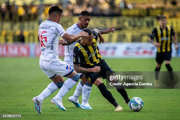 Brian Lozano and Yonathan Rodríguez of Nacional fight for the ball with Kevin Mendez of Peñarol during the Torneo Apertura 2023 match between Peñarol...