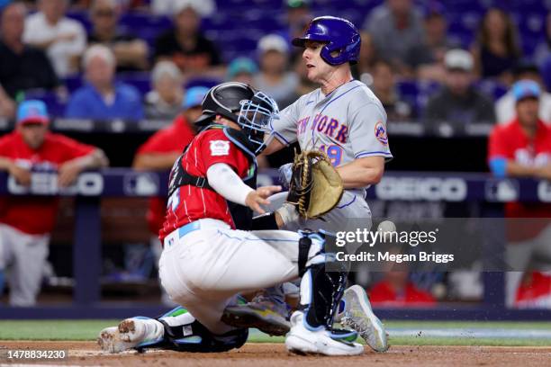 Mark Canha of the New York Mets slides home safe past Nick Fortes of the Miami Marlins during the second inning at loanDepot park on April 01, 2023...