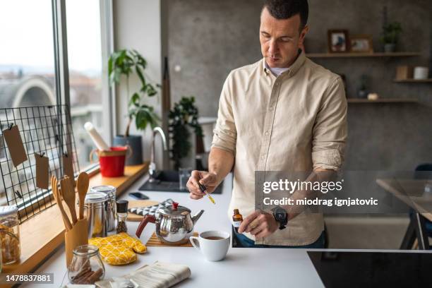 hombre añadiendo una gota de aceite de cbd en el té - cannabinoid fotografías e imágenes de stock