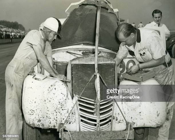 Driver Ed Samples looks on as his mechanic Bob Osiecki makes adjustments to the engine of his Modified stock car before a race at Greensboro...