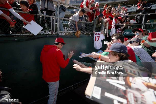 Shohei Ohtani of the Los Angeles Angels walks back to the clubhouse as fans try to get his autograph before their game against the Oakland Athletics...