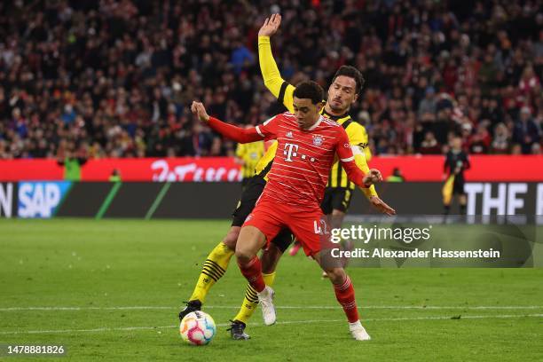 Jamal Musiala of Bayern München runs with the ball with Mats Hummels of Borussia Dortmund during the Bundesliga match between FC Bayern München and...