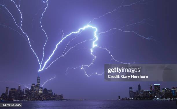 Lightning bolts strike One World Trade Center in New York City as it fans out over the Hudson River and Jersey City, New Jersey during a thunderstorm...