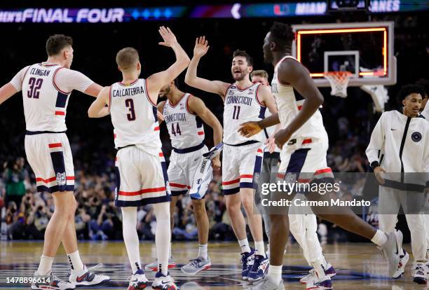 Alex Karaban of the Connecticut Huskies and teammates celebrate a three-point basket at the end of the first half against the Miami Hurricanes during...