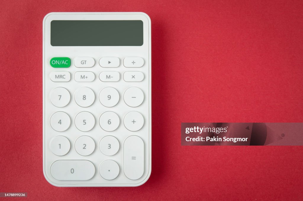 White calculator with copy space against a red background.