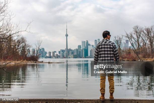 rear view of man standing staring the views of toronto - lake ontario stock pictures, royalty-free photos & images