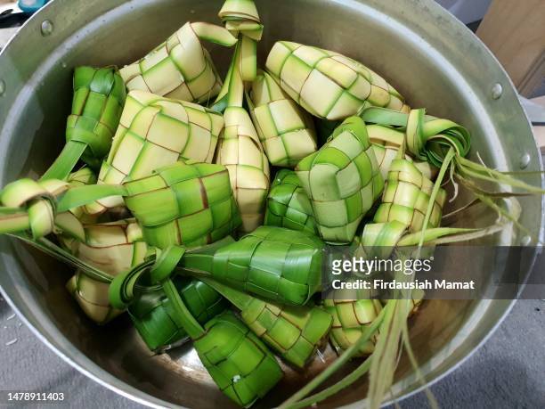 close up of ketupat; rice compressed and wrapped in woven coconut leaves ready to be boiled in a pot - ketupat stock pictures, royalty-free photos & images