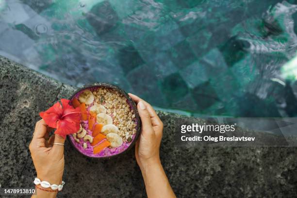 tropical vacations concept. healthy breakfast with smoothie bowl on swimming pool edge - blue bowl fotografías e imágenes de stock