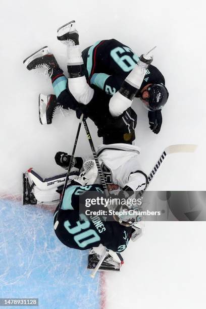 Adrian Kempe of the Los Angeles Kings falls against Vince Dunn and Martin Jones of the Seattle Kraken during the second period at Climate Pledge...
