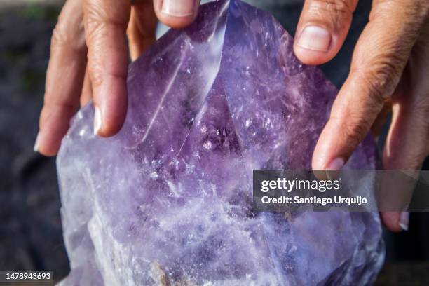 close-up of woman hands touching a large amethyst crystal - amatista fotografías e imágenes de stock