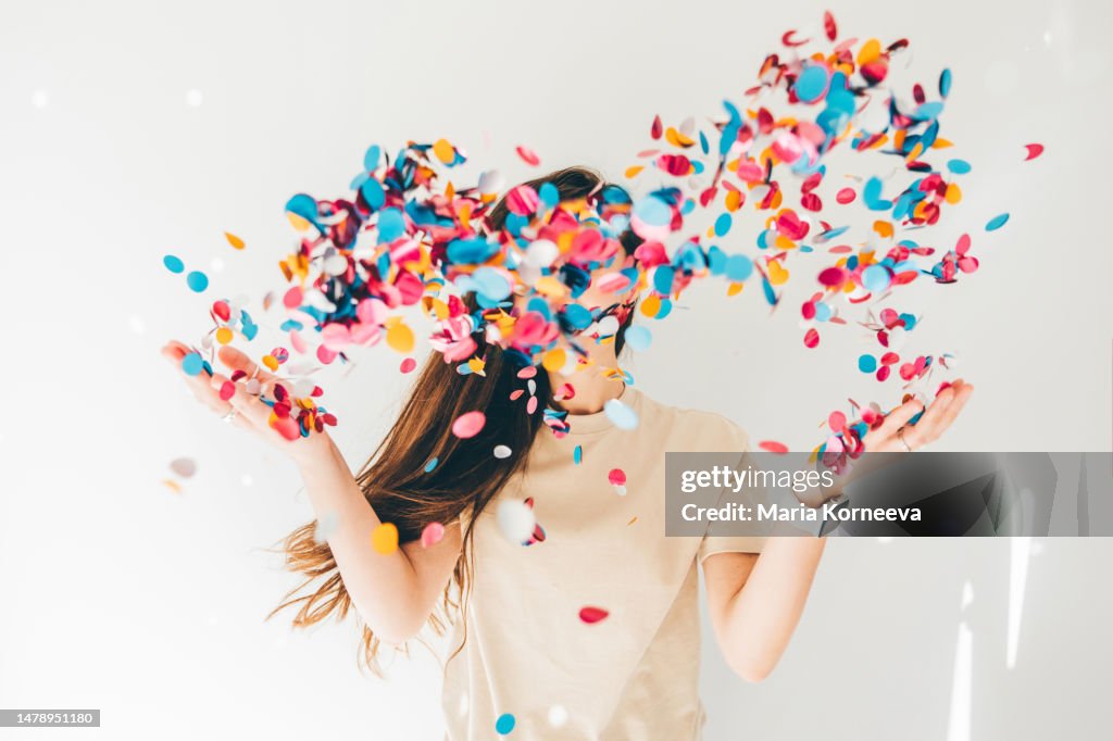 Woman celebrating with confetti on white background.