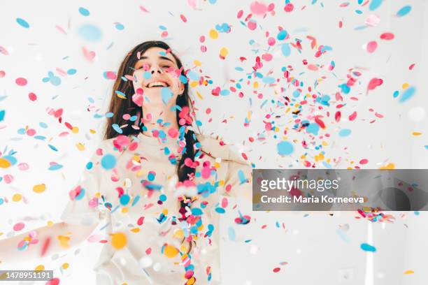 woman celebrating with confetti on white background. - confetti explosion stock-fotos und bilder