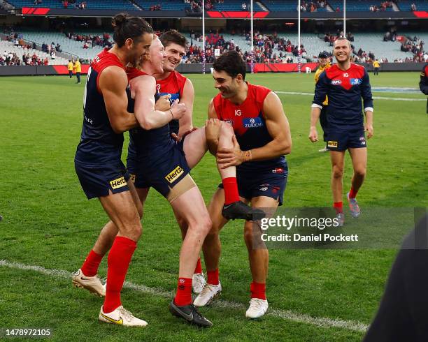 Brodie Grundy, Angus Brayshaw and Christian Petracca of the Demons attempt to carry Clayton Oliver of the Demons off the field during the round three...