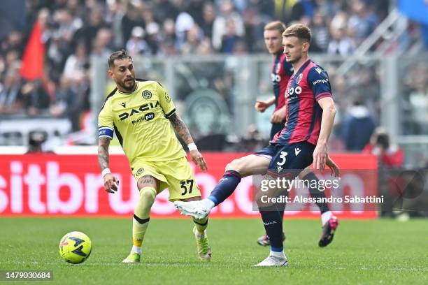 Stefan Posch of Bologna FC passes the ball whilst under pressure from Roberto Pereyra of Udinese Calcio during the Serie A match between Bologna FC...