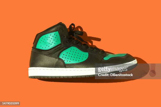 black and green basketball sneakers, on a orange background. concept for sneaker, basketball, retro, fashion, collection and casual - sneakers stock pictures, royalty-free photos & images