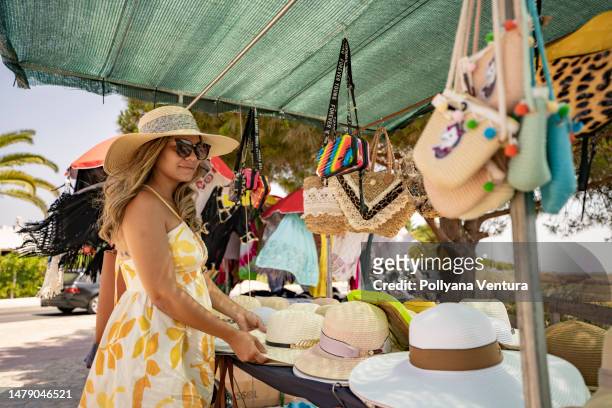 woman buying sun hat on the beach - algarve holiday stock pictures, royalty-free photos & images