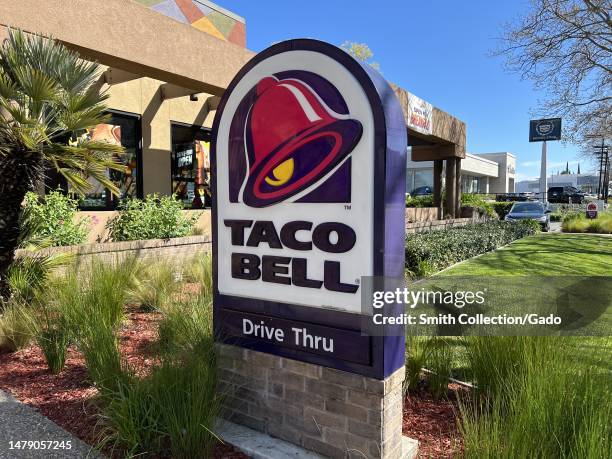 Taco Bell drive-thru open for business with lush green plants and clear sky in a residential neighborhood, Walnut Creek, California, March 27, 2023.