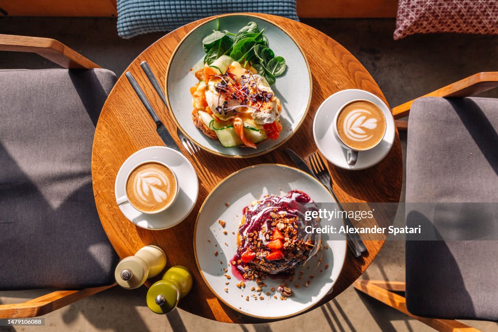 Brunch with sweet pancakes and Eggs Benedict with salmon served in restaurant