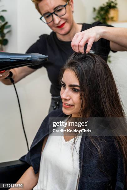 young woman in a beauty salon having her hair dried - hand holding hair dryer stock pictures, royalty-free photos & images