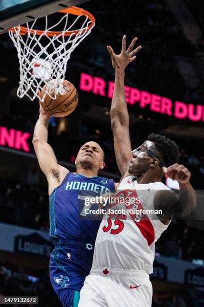 Bryce McGowens of the Charlotte Hornets drives to the basket while guarded by Christian Koloko of the Toronto Raptors in the second quarter during...