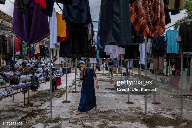 Student walks among the clothes drying at the Islamic boarding school Al-Fatah Temboro during the holy month of Ramadan on April 02, 2023 in Magetan,...