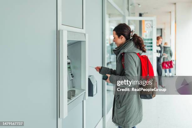 young woman withdraws money from atm machine at the bank - cashier stock pictures, royalty-free photos & images