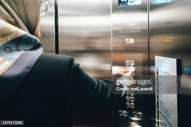 a young businesswoman pressing the button in an elevator - röra mot bildbanksfoton och bilder