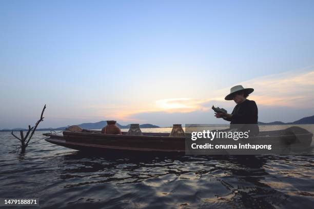 elder fisher man take dinner on boat during hunt the fish in reservoir ,chonburi of thailand - food silhouette stock pictures, royalty-free photos & images