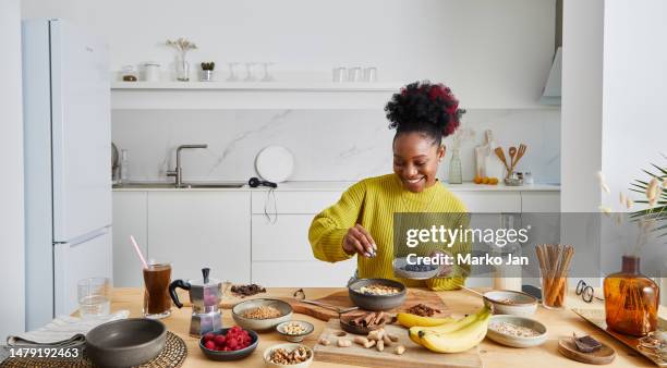 glückliches junges mädchen, das ein gesundes frühstück zubereitet - eating nuts stock-fotos und bilder