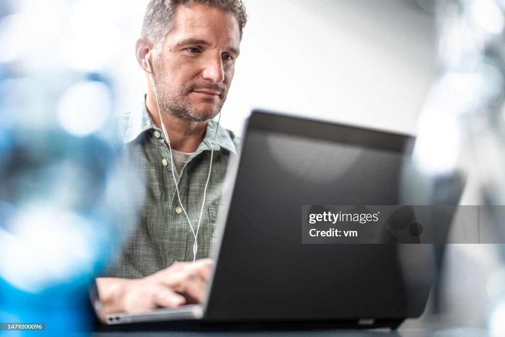 Man in earphones working on laptop