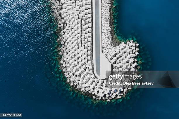 aerial drone view of concrete breakwater construction. coastal protection barrier - barrikade stock-fotos und bilder