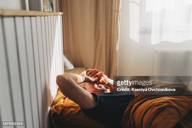 man stretch his hands after waking up in bed at morning with sunlight - wake water stock pictures, royalty-free photos & images
