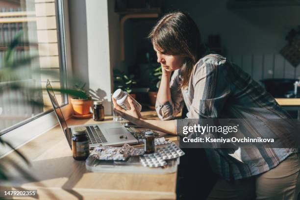 mature woman with blister pack of pills and smartphone in hand using online pharmacy store, buying pharmacy on internet, ordering medicine online at home. - complément vitaminé photos et images de collection