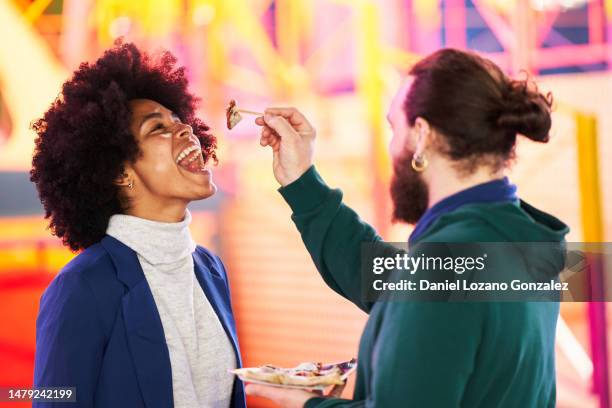 happy couple eating a crepe together in a fair - crêpe pancake photos et images de collection