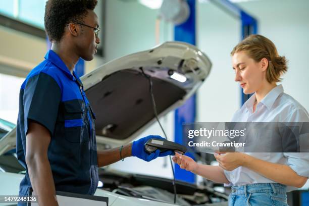 males african mechanic receive contactless payment from females customer in car repair shops after they check all complete after he fixes the car. - second hand car stock pictures, royalty-free photos & images