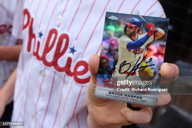 Fan holds a baseball card signed by Bryce Harper before the game against the Texas Rangers at Globe Life Field on April 01, 2023 in Arlington, Texas.