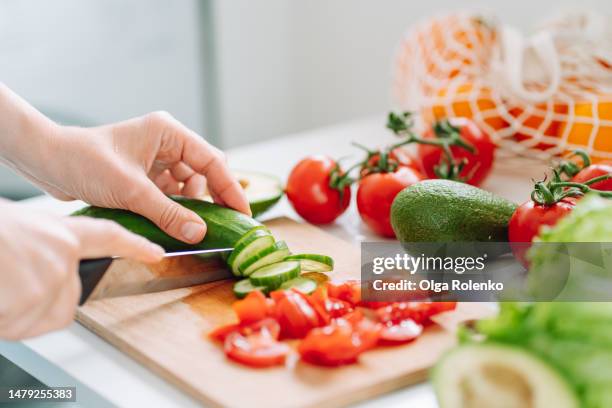 unrecognizable woman hands cutting zucchini on wooden chopping board on the table - chop stock pictures, royalty-free photos & images