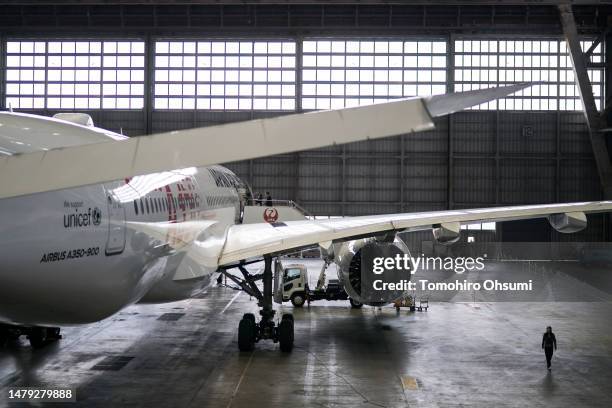 An employee walks near an Airbus A350 airplane for Japan Airlines parked during an entrance ceremony in a hangar at Haneda Airport on April 03, 2023...