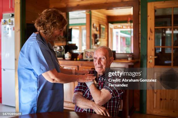 female doctor examining a old patient at his home - rural scene stock pictures, royalty-free photos & images
