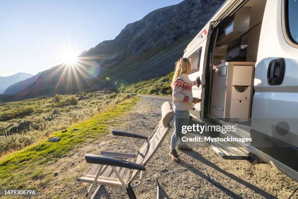 frau, die bei sonnenuntergang in ihr wohnmobil steigt, van-life-konzept - campingstuhl stock-fotos und bilder