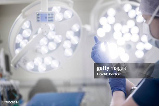 female surgeon putting on surgical gloves in operation room - medical glove stock pictures, royalty-free photos & images